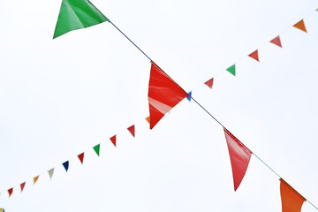 Colorful triangular Flags Hanging in the white sky outdoor.