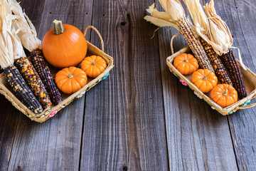 Seasonal set up for Halloween or Thanksgiving, desiged with pumkins, corn, and wicker baskets with a wooden backdrop. 