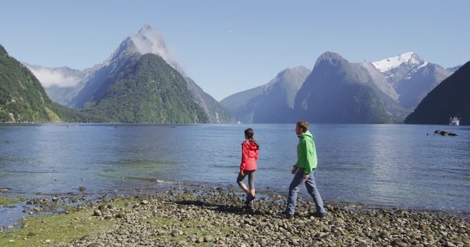 New Zealand Tourists hiking in Milford Sound by Mitre Peak in Fiordland. Couple on New Zealand travel visiting famous tourist destination and attraction on south island, New Zealand.