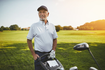 Senior man standing with his clubs on a golf course