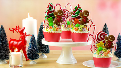On-trend candyland festive Christmas cupcakes in colorful party table setting.