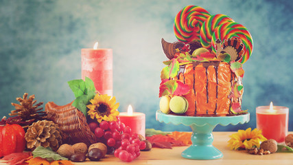 On trend Thanksgiving candyland novelty drip cake with colorful Fall leaves and cornucopia table setting with retro filter.