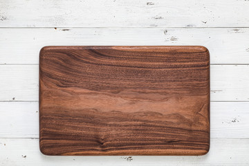 Handmade black walnut rectangular chopping board on a white wooden board top. Walnut texture background.	