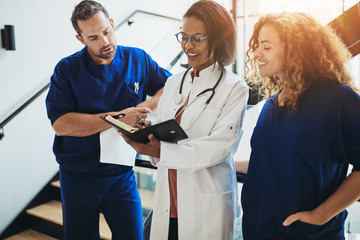 Diverse doctors discussing paperwork together in a hospital corr