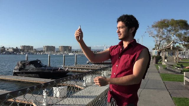 Handsome young tourist taking a pan shot of the harbor with his smart phone