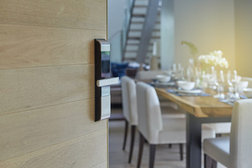 Wood door half open with digital knob door or handle in front of blur dining interior background