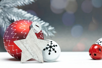 christmas tree decorations on grey background with blurred silver fir tree branch and light spots