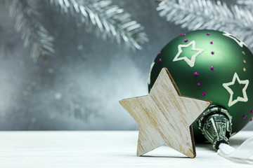 green christmas ball and wooden decorative star on blurred silver background