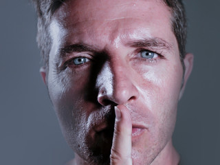 Obraz premium young handsome and attractive man with finger on his closed mouth warning to shut up and not to speak in censorship and freedom of speech coercion