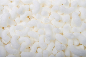 Flat lay of biodegradable packing peanuts. Biodegradable packing peanuts are made from natural, nontoxic sources, such as wheat and corn starch. They dissolve in water and can be put in compost piles.