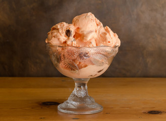Rum and raisin icecream in glass bowl on rustic wooden table