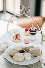Traditional English afternoon tea: scones with clotted cream and jam, strawberries, with various...