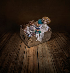 Fototapeta premium Variety dolls in a vintage box in dark empty room 