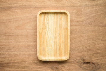 Top view of unused brand new brown handmade wooden dish plate on wooden table background