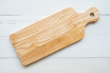 Top view of unused brand new brown handmade wooden cutting board on white wooden table background