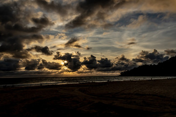 Fototapeta premium Dramatic clouds over the ocean as the sun sets and the sky turns dark, Karon Beach, Phuket Thailand.