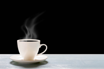 Hot cup of coffee on wooden table on dark background