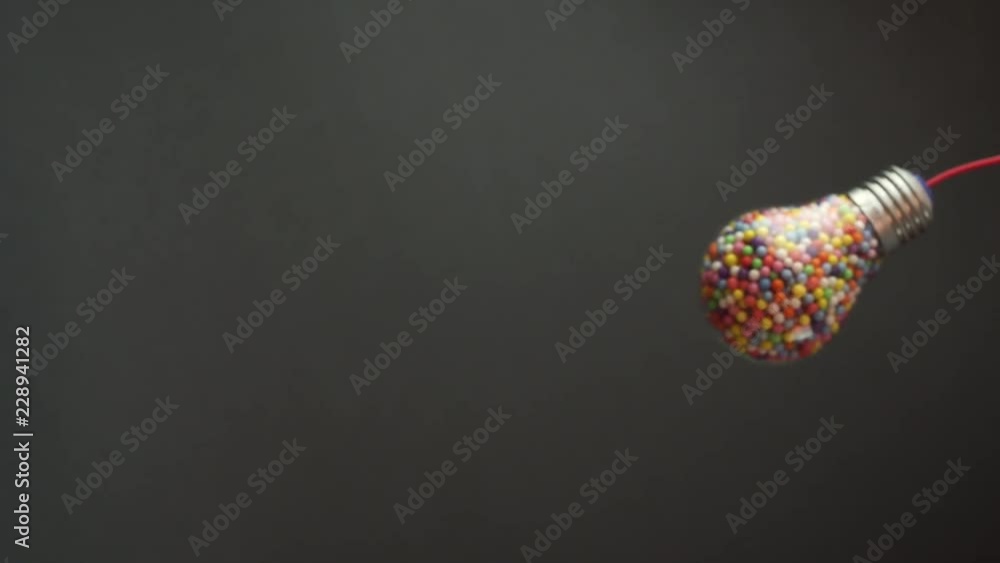 Aufkleber lightbulb filled with colored ball dark background, macro view. best idea concept.