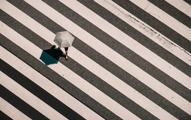 Aerial view of people crossing a big intersection in Tokyo, Japan . Street photo, umbrella have one leg