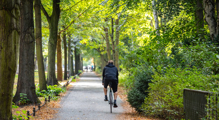 Tiergarten city park in Berlin, Germany. View of a young man riding a bike