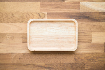Top view of unused brand new brown handmade wooden dish plate on wooden table background
