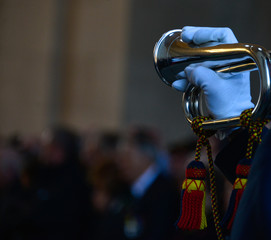 polished brass bugle held in playing position with white gloved hand at memorial ceremony