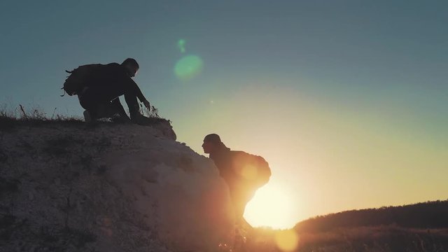 Climber helping teammate climb, the man with the backpack reached out a helping hand to his friend. Hiker helping friend while trekking on hill. Tourist man helps someone to climb the mountain.