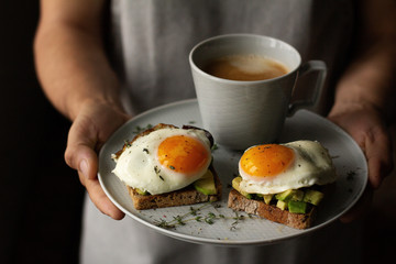 man's hands hold a tray of coffee and toast
