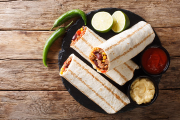 Mexican popular grilled burrito snack with beef and vegetables and with sauces close-up. horizontal...