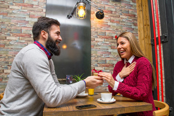 Man giving a present to his girlfriend in cafe and she is surprise
