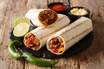 Traditional grilled burritos with beef and vegetables served with sauces close-up. horizontal