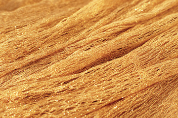 The texture of the mesh fabric. Golden mesh fabric creates a textural background. Golden fabric for design and decoration.