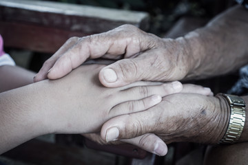 Fototapeta premium Hands holding together takecare of Asian elderly or grandfather hands wrinkled skin touching teenage with feeling take care of Love. Relationship of Family father day concept