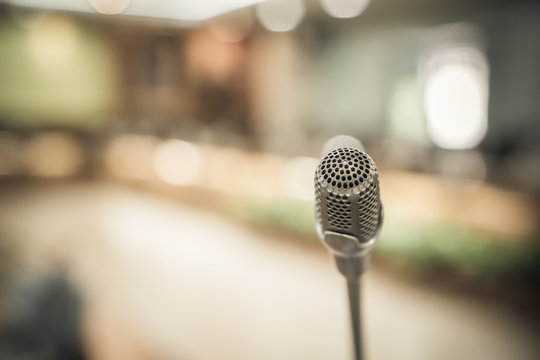 Front Microphone on abstract conference hall prepare for speaker on stage in seminar room, Business meeting and education in teaching classroom or Event light convention hall Background.