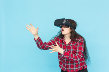 Future, technology and people concept - Surprised young woman wearing vr-glasses on blue background