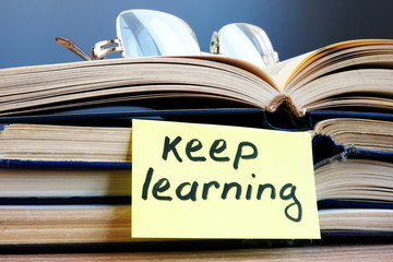Keep learning. Open book and glasses on the table.