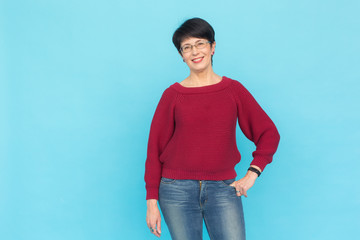 Fashion, people and style concept - Beautiful mid-aged woman in red sweater and glasses on blue...