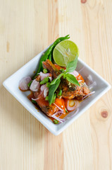 Spicy salad of canned sardines fish on wooden table