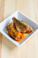 fish in tomato sauce - canned fish in white dish on wooden table