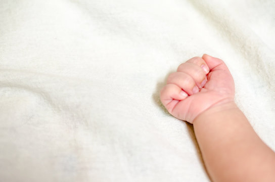 Newborn baby hand on white bed