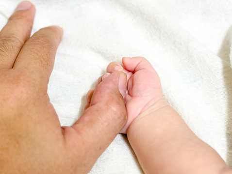 Father's fingers on baby hand