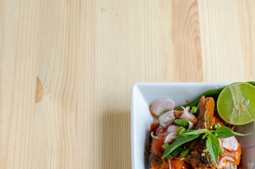 Spicy salad of canned sardines fish on wooden table