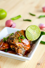 Spicy salad of canned sardines fish on wooden table