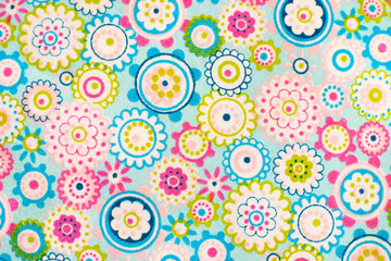 Fototapeta na wymiar The texture of cotton fabric. Colorful fabric with a pattern of circles and flowers creates the background. Cotton fabric for sewing clothes or bedding.