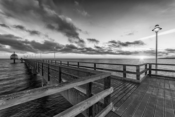 Fototapeta na wymiar Seebrücke Zinnowitz auf der Insel Usedom mit Tauchglocke bei Sonnenaufgang in schwarz weiß