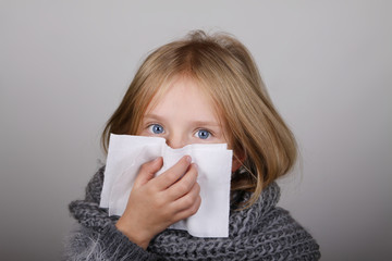 cute blond hair little girl blowing her nose with paper tissue. Child winter flu allergy health care concept