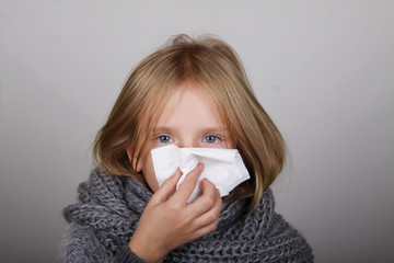 cute blond hair little girl blowing her nose with paper tissue. Child winter flu allergy health care concept