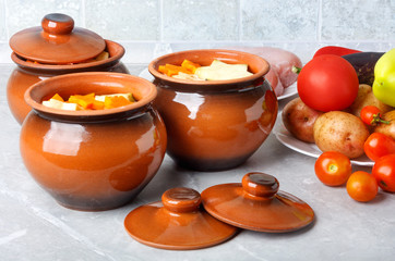 Traditional rustic home vegetable  ragout in three clay pots on beautiful table top.