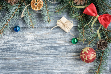 Christmas or New Year decoration background with fir branches, cones, balls, marshmallows on grey wooden board.