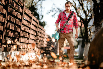 Portrait of handsome man with leaf blower, home gardening details